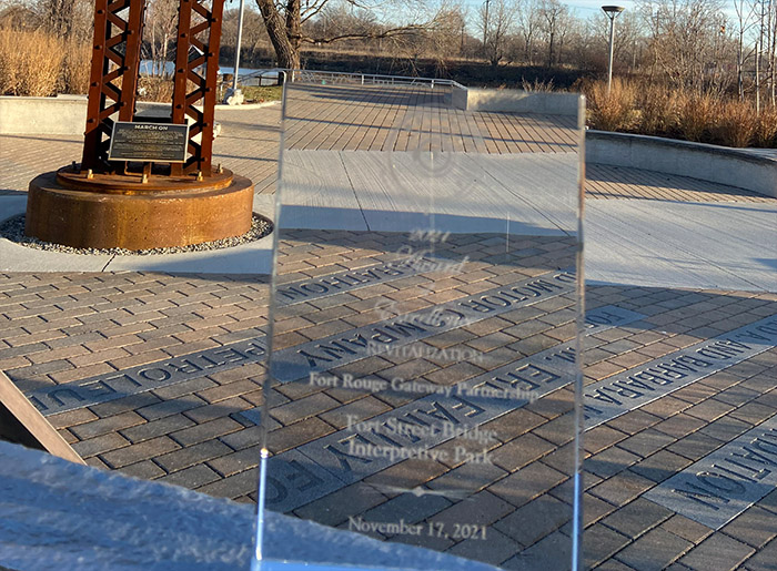 This image shows a clear, crystal plaque against the backdrop of fort street bridge park